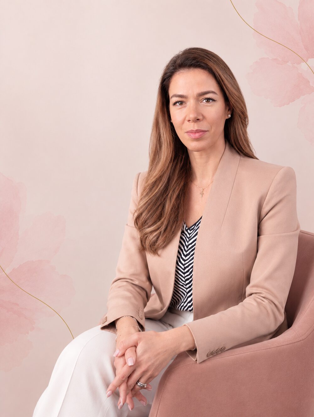 Alexandra Pădurariu, așezată pe un fotoliu, purtând un sacou bej, într-o încăpere cu pereți decorați cu motive florale roz